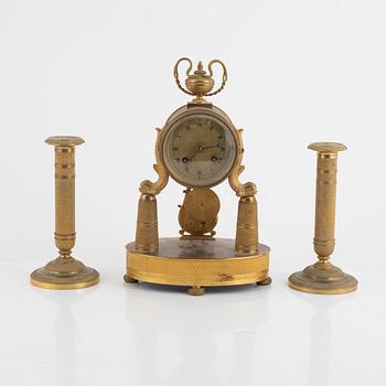 An Empire-style gilt bronze mantel clock and a pair of candlesticks, 20th century.