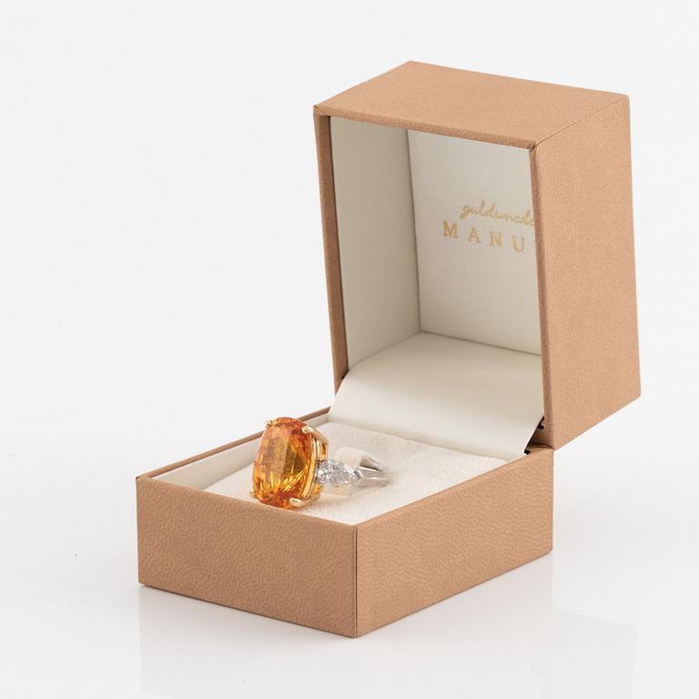 An 18K white gold ring set with a cushion shaped orange-yellow sapphire.