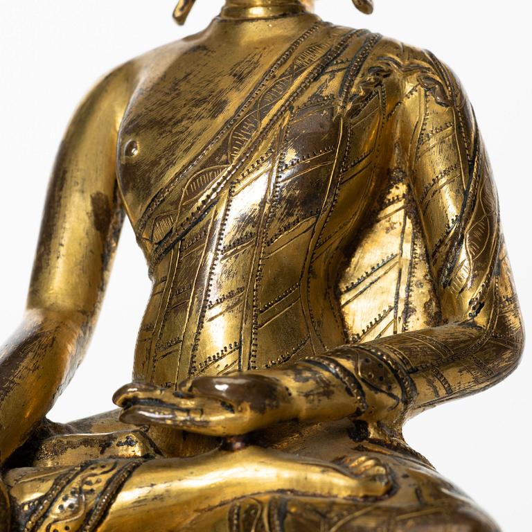 A gilt copper-alloy figure of Aksobhya Buddha, 14th/15th century, Tibet or Nepal.