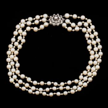1405. A three strand cultured pearl necklace with a clasp decorated with diamands.