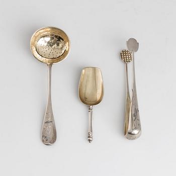 A Russian parcel-gilt tea caddy spoon, sugar thongs and sugar sifter, maker's mark Grigory Spitnev, Moscow, 1898-1914.