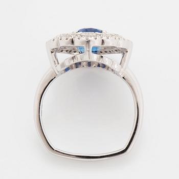 A platinum ring set with a faceted sapphire and round brilliant-cut diamonds.