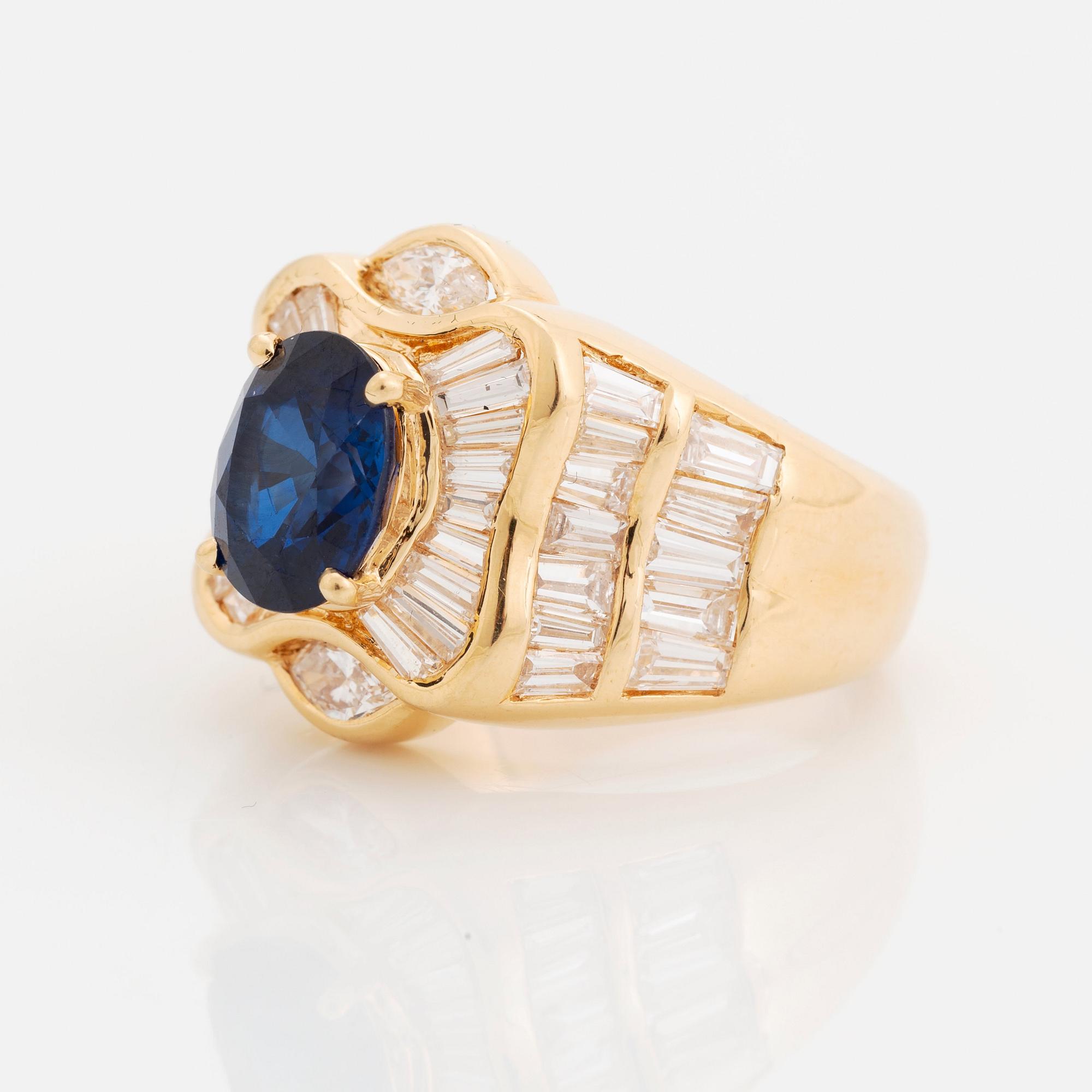 An 18K gold Junod ring set with a facted sapphire and tapered baguette-cut diamonds.