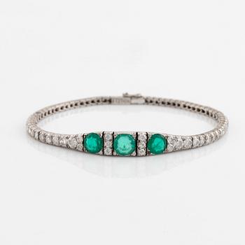 A platinum bracelet set with emeralds and round brilliant-cut diamonds.