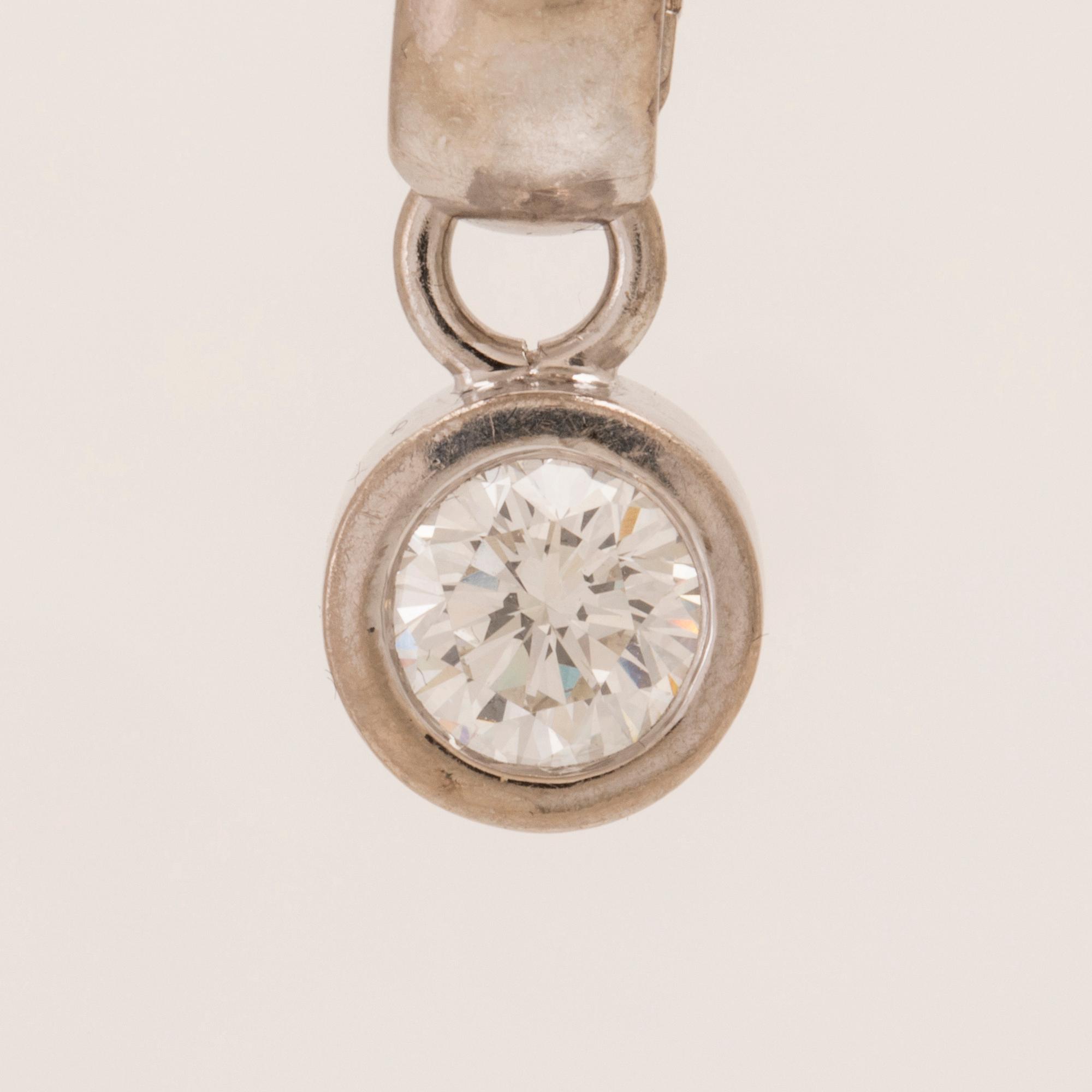 An 18K white gold pendant set with a round brilliant-cut diamond.