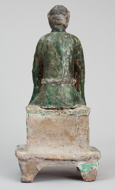 A green and yellow glazed pottery figure of a guardsman, seated on a postament, Ming dynasty.