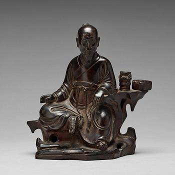 A bronze sculpture of a seated scholar with books, Qing dynasty (1644-1912).