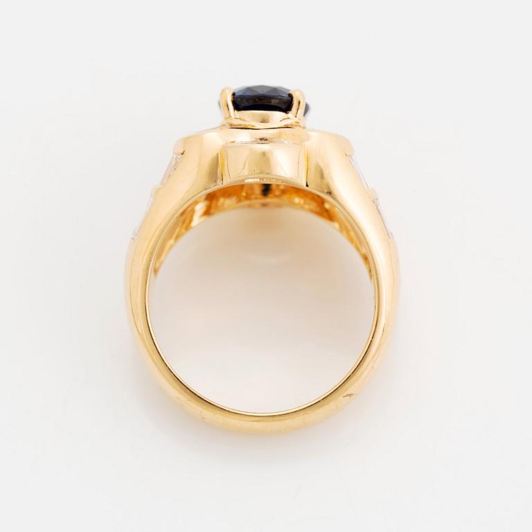 An 18K gold Junod ring set with a facted sapphire and tapered baguette-cut diamonds.