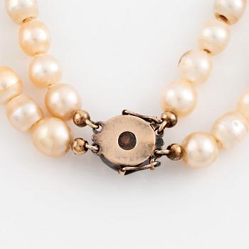 A two strand natural pearl necklace with a silver  clasp set with an old-cut diamond.