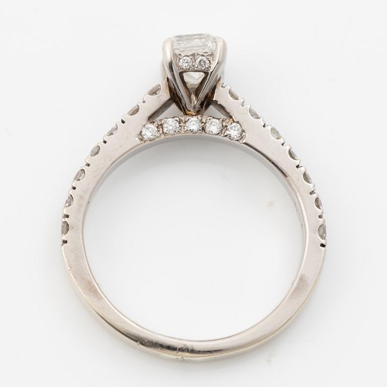 18K white gold ring set with an emerald-cut diamond and round brilliant-cut diamonds.