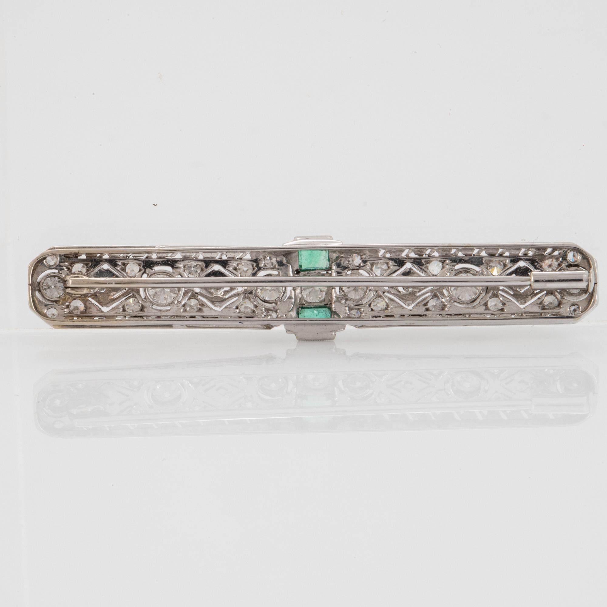 An 18K white gold brooch set with old- and eight-cut diamonds and faceted emeralds.