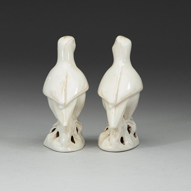 A pair of white and red glazed figures of parrots, late Qing dynasty.