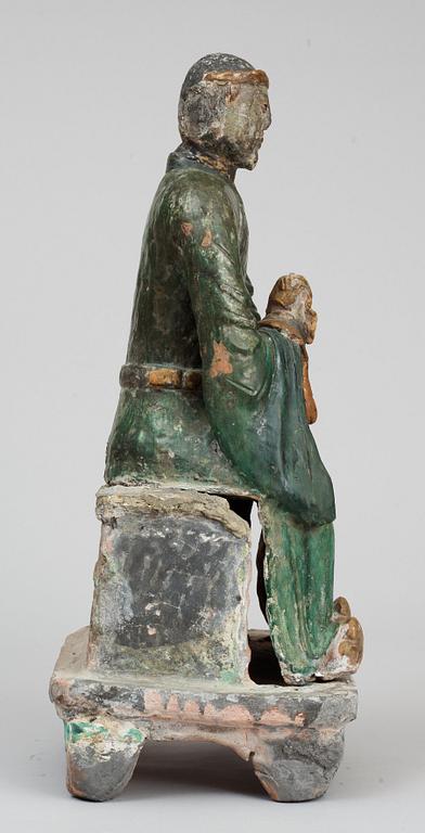 A green and yellow glazed pottery figure of a guardsman, seated on a postament, Ming dynasty.