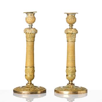 A pair of French Empire ormolu candlesticks, ca 1820's.
