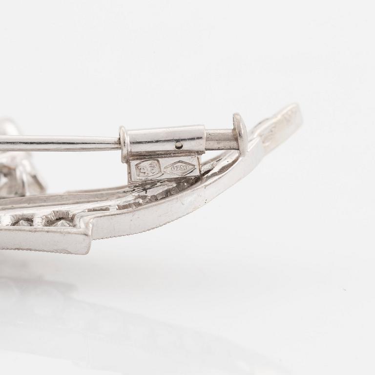 An 18K white gold brooch set with round brilliant-cut diamonds.