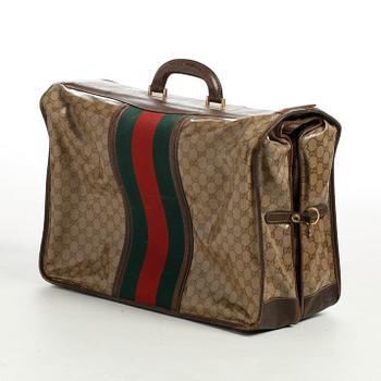 GUCCI, a monogramed waxed canvas garement cover bag.