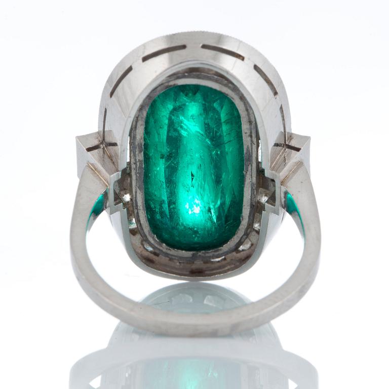 A platinum ring set with a cabochon-cut emerald ca 7 cts and brilliant and baguette-cut diamonds.