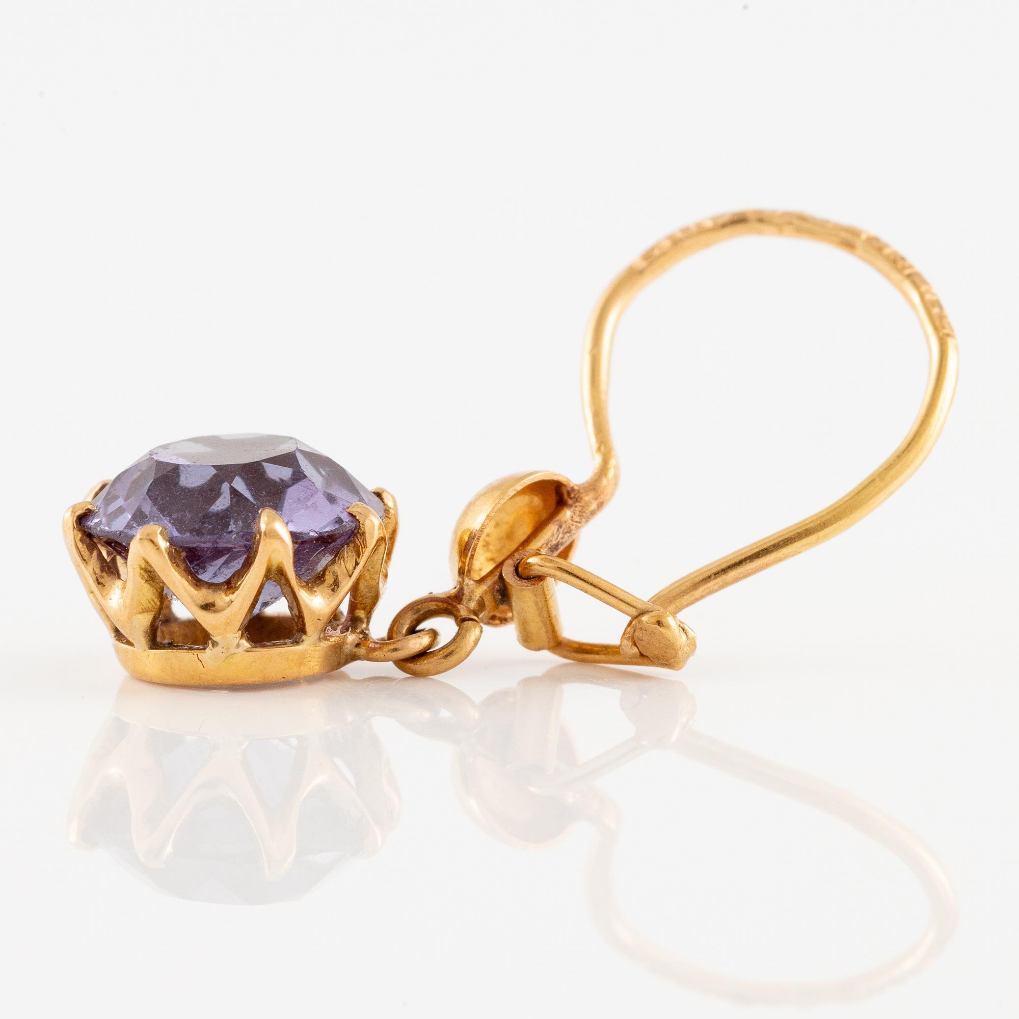 A pair of earrings in 18K gold with purple stones.