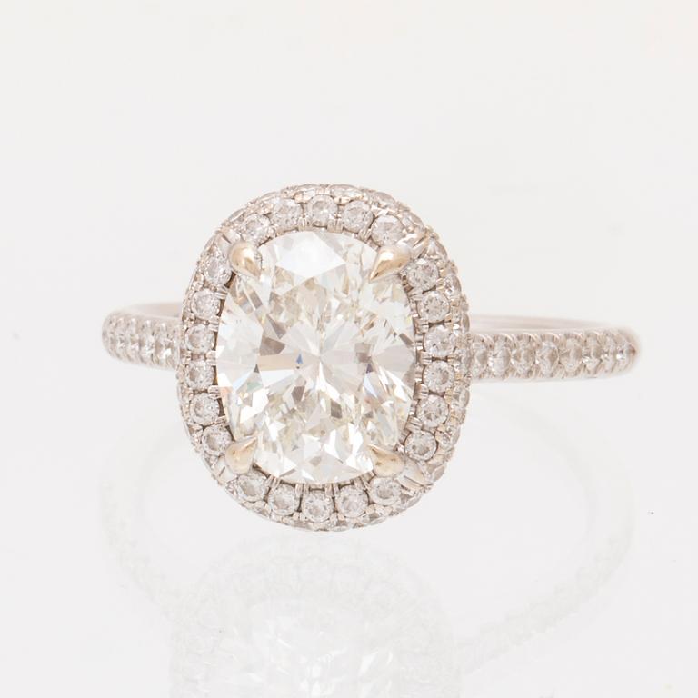 An 18K white gold ring by James Allen, set with an oval brilliant cut diamond in a halo of round brilliant cut diamonds.