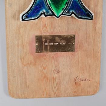 a stoneware wall plaque, signed with a stamp on the wooden board.