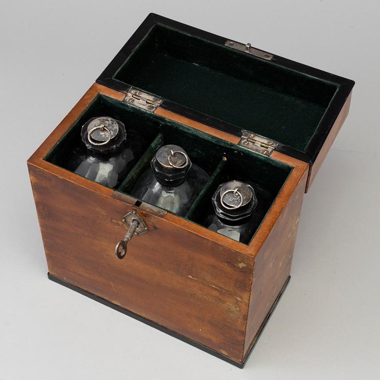 A mid 19th century mahogany veneered box with three glass bottles.