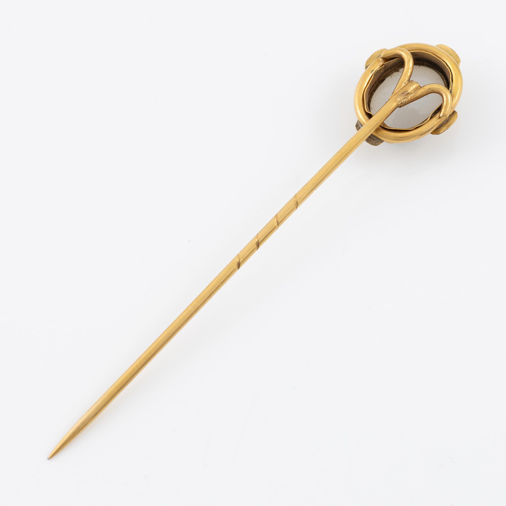 Brooch pin of low-grade gold with a white-blue stone.