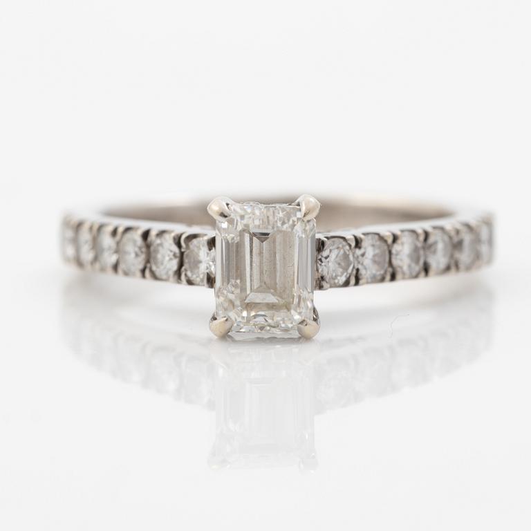 18K white gold ring set with an emerald-cut diamond and round brilliant-cut diamonds.