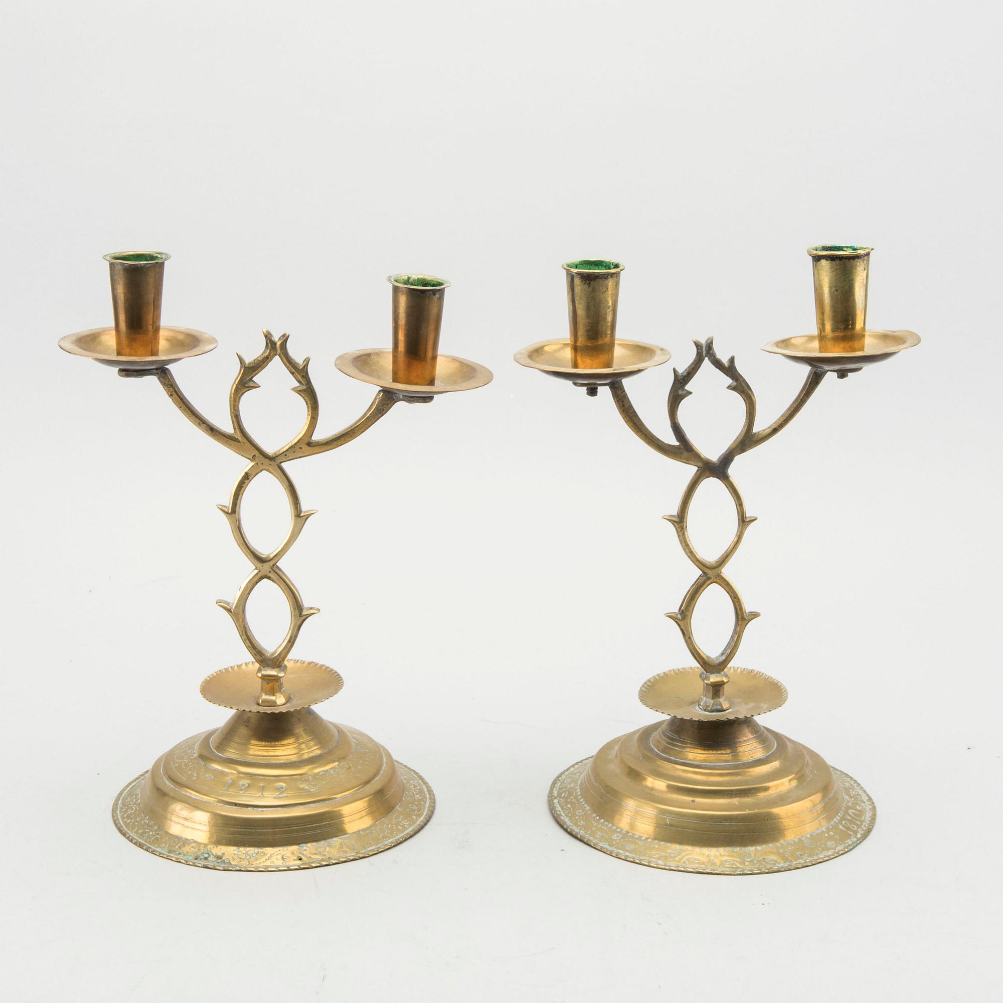 A pair of brass candelabras dated 1810 and 1812.