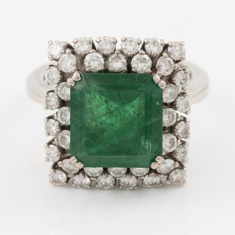 Ring in 18K white gold set with a faceted emerald and round brilliant-cut diamonds.