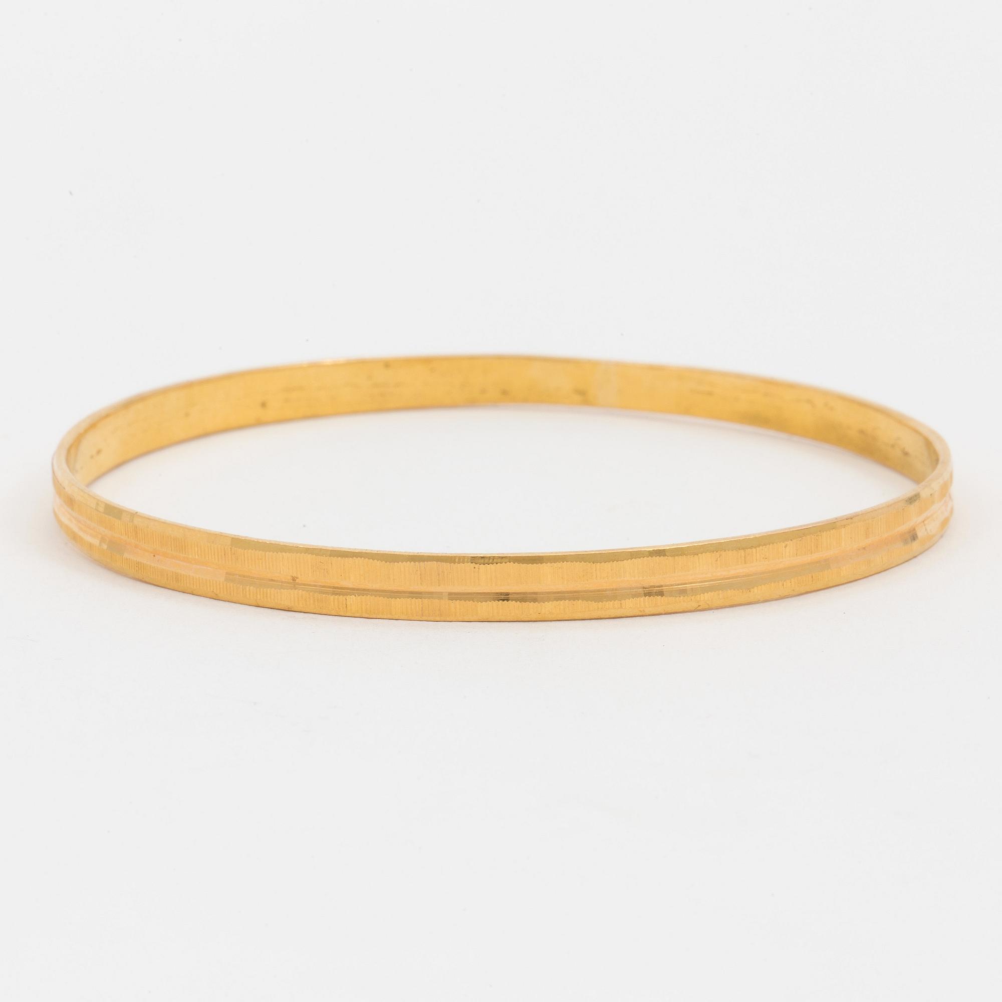 A bangle with a textured surface. 14K gold.