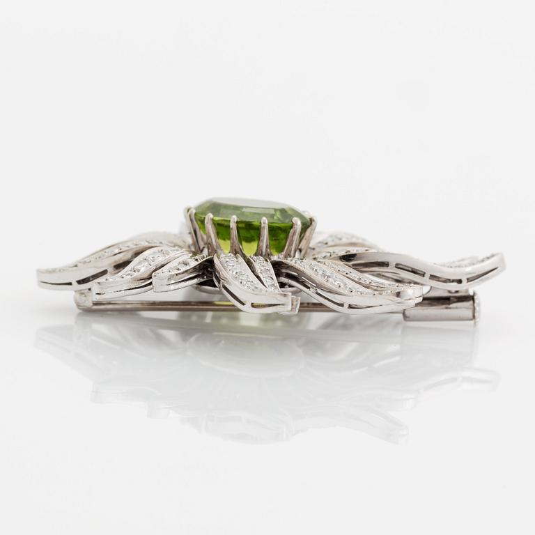 An 18K white gold brooch set with a faceted peridot and eight-cut diamonds.