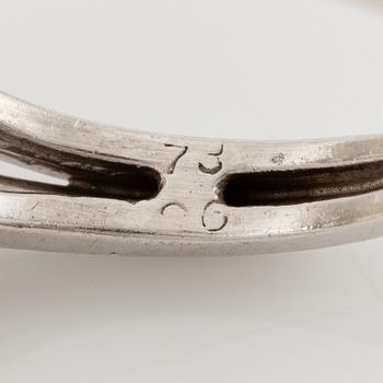 A platinum ring set with a pear-shaped yellow diamond and round brilliant-cut diamonds.