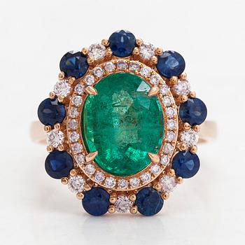 A 14K rosegold ring with an emerald  2.48 ct, sapphires ca 1.17 ct, and diamonds ca. 0.48 ct. With IGI certificate.