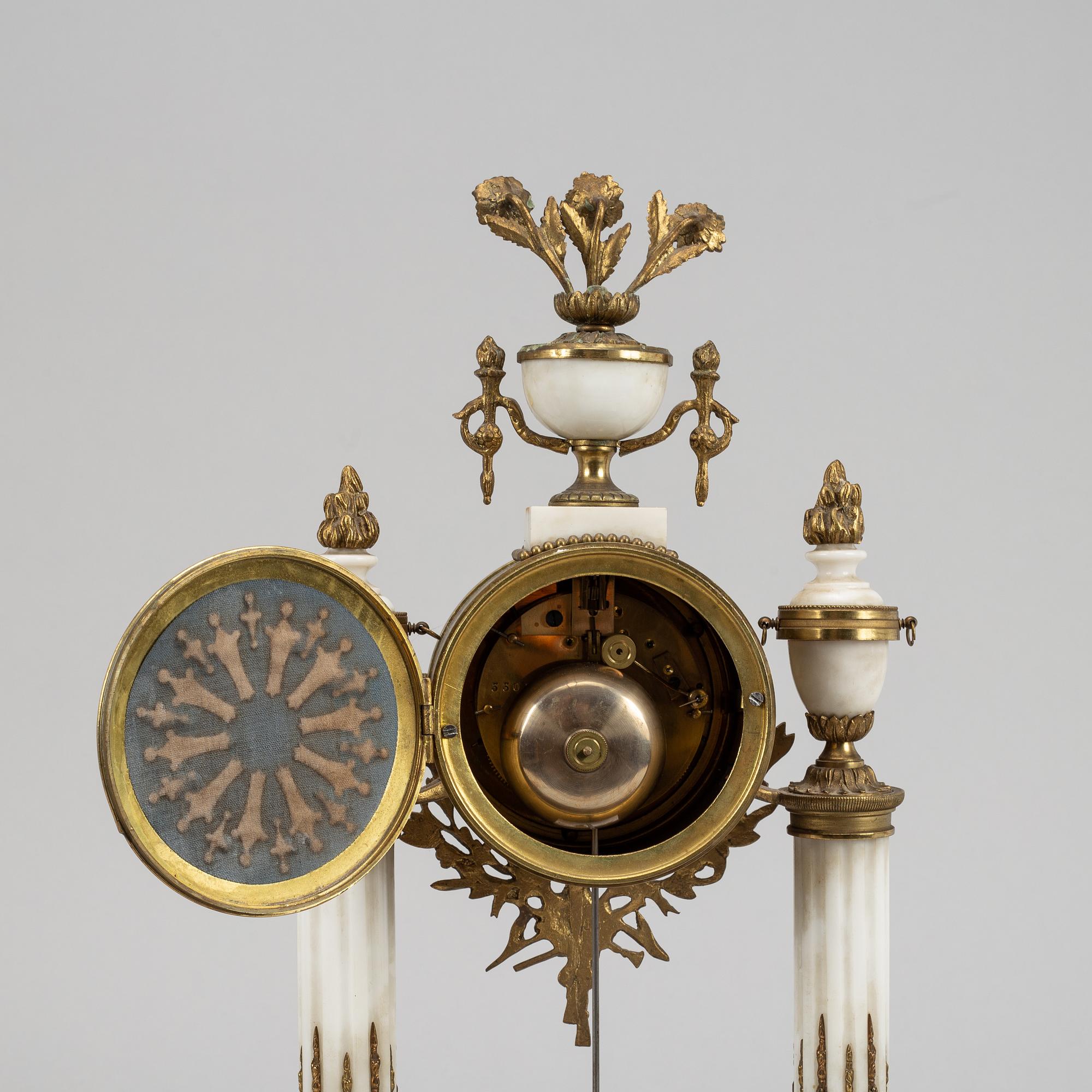 A Louis XVI style pendulum clock and a pair of candelabra, early 20th century.