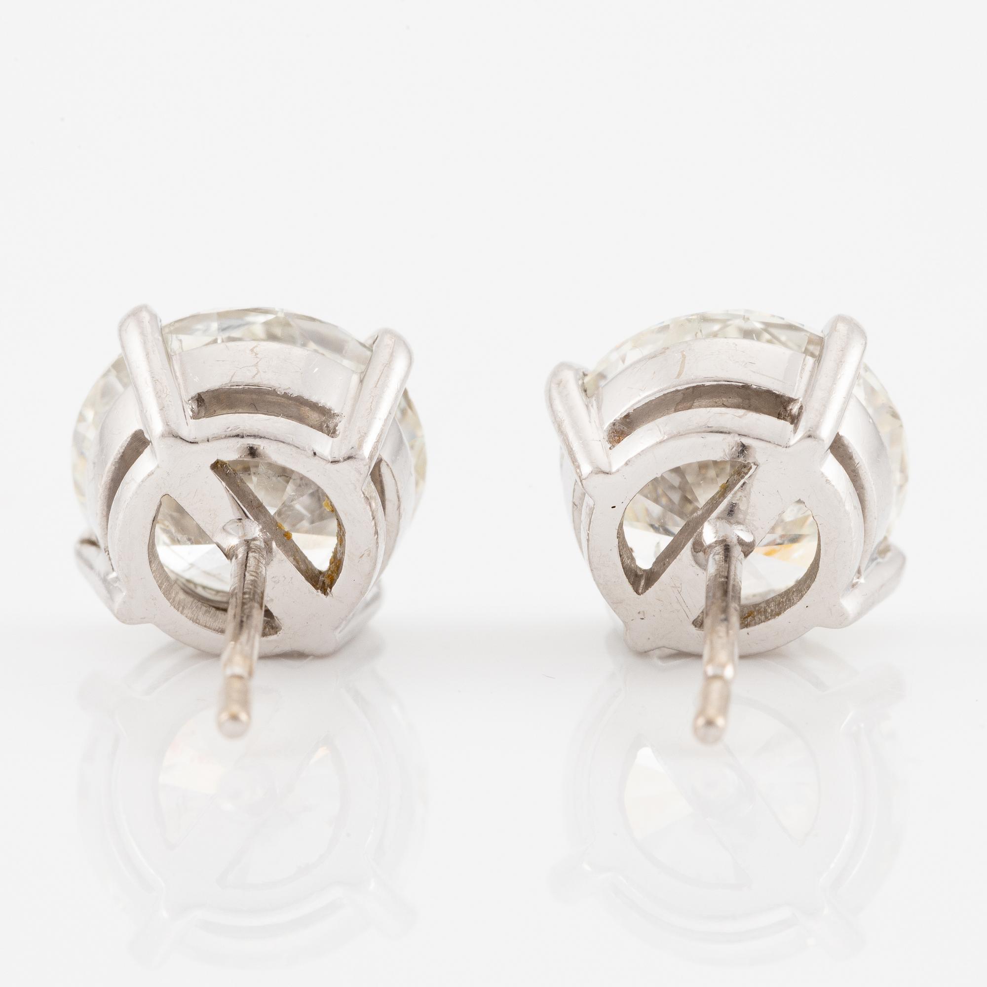 A pair of earrings in 18K white gold set with two round brilliant-cut diamonds.
