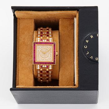 A Bulgari wristwatch in 18K gold set with step-cut rubies and round brilliant-cut diamonds.