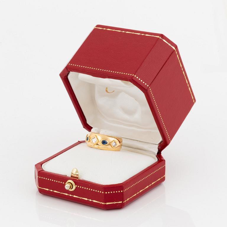 An 18K gold Cartier ring set with step-cut diamonds and faceted sapphires.
