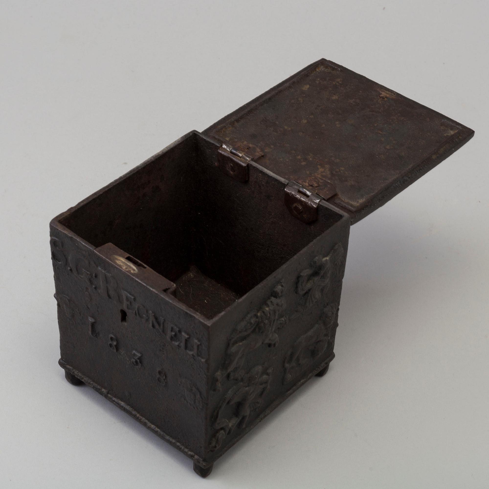 An empire cast iron tobacco box, dated 1838.