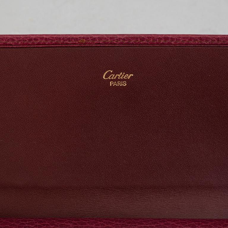 A burgundy leather bag from les must de Cartier.