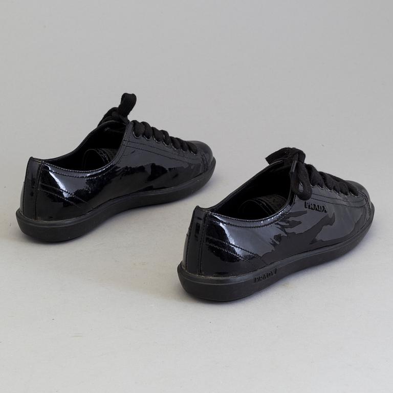 A pair of PRADA black patent leather sneakers.