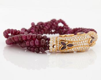 A Cartier chimera head bracelet in 18K gold set with round brilliant-cut diamonds and faceted rubies.