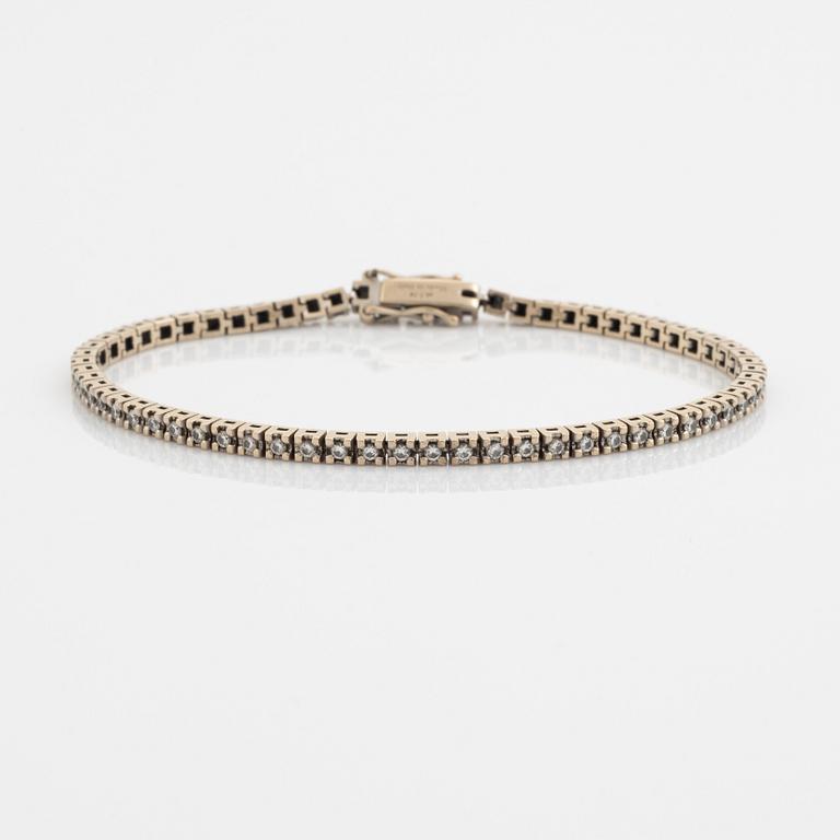 An 18K gold tennis bracelet set with round brilliant-cut diamonds.