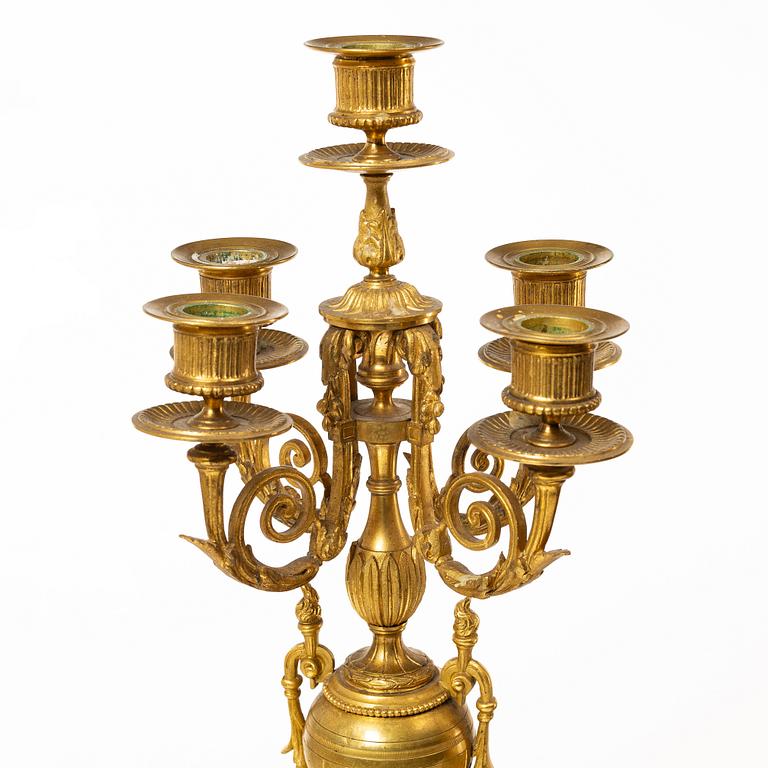 A mantle clock and a pair of candelabra, Louis XVI style, ca 1900.