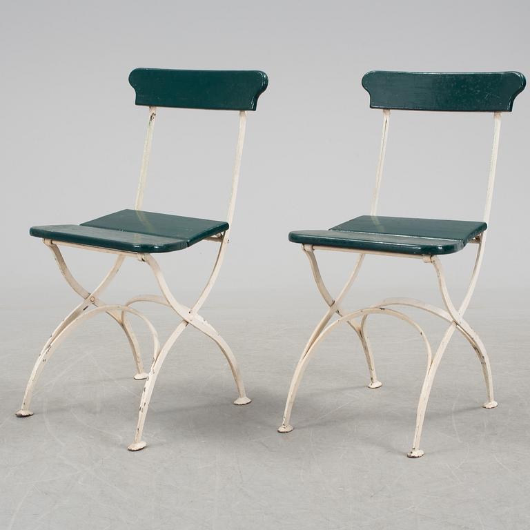A pair of cast iron chais with wooden seats and a cast iron table, early 20th century.