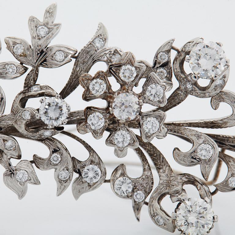 An 18K white gold brooch set with round brilliant-cut diamonds.