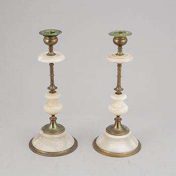 An alabaster mantle clock and pair of candlesticks, circa 1900.