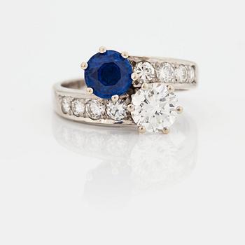 903. A CROSS-OVER RING set with a round mixed-cut sapphire and round brilliant-cut diamonds.