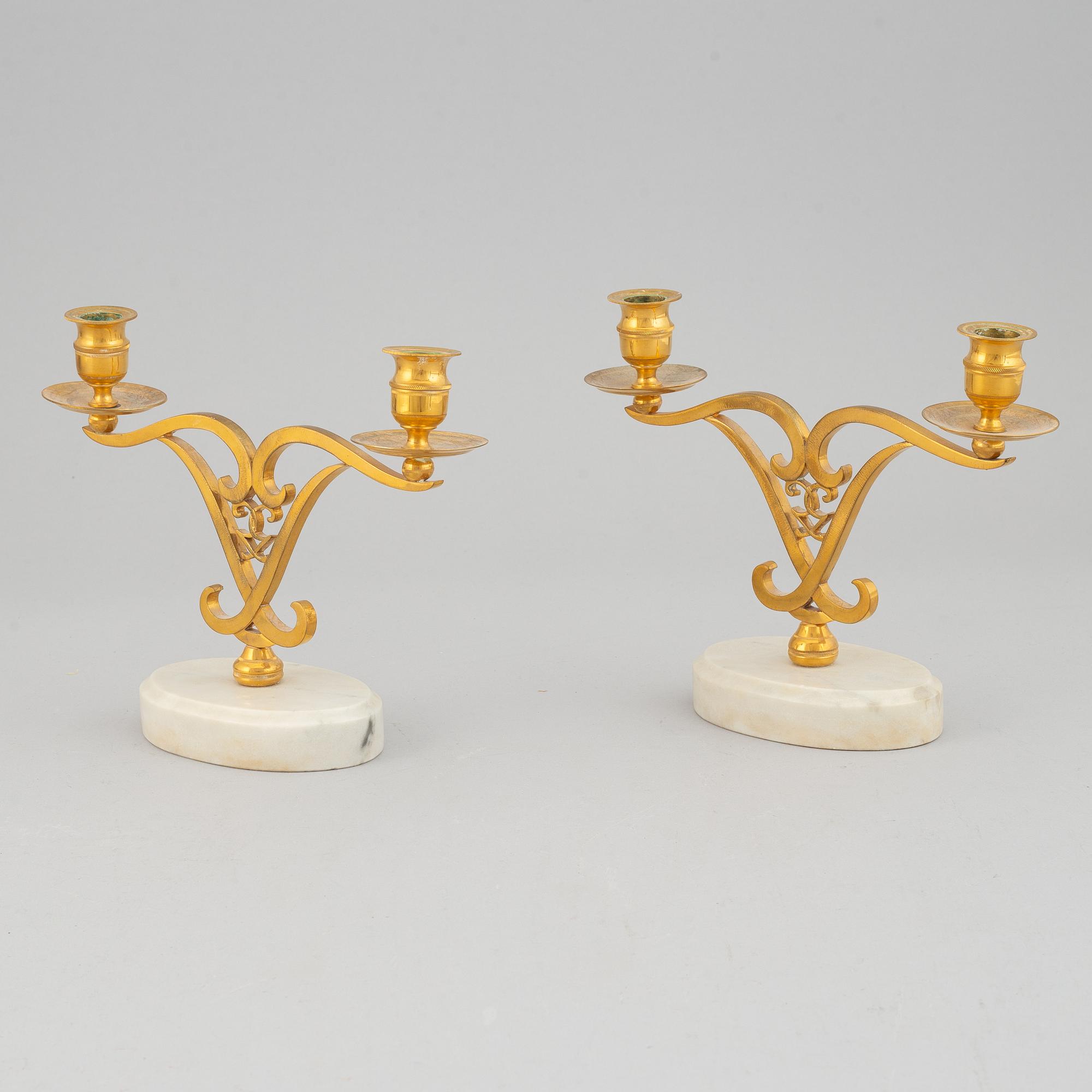A pair of brass candle sticks om marble stands from the middle of 20th century.