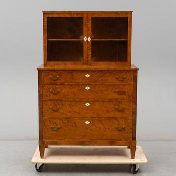 a chest of drawers with a vitrine cabinet from the early 20th century.