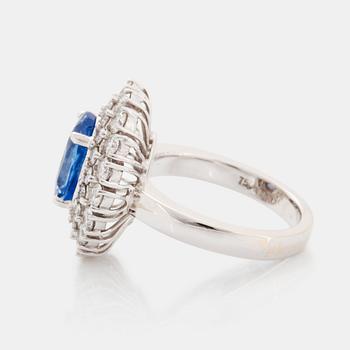 An 18K white gold ring set with an oval faceted sapphire and round brilliant-cut diamonds.